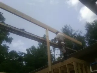 Carpenter setting a ridge beam over a new addition frame — Ice Dam Removal by Roofing Brothers in Saint Georges