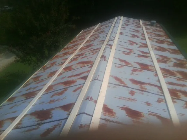 Rusted metal roof panels with new wood purlins before replacement — Storm Damage Roof Repair in Saint Georges by Roofing Brothers