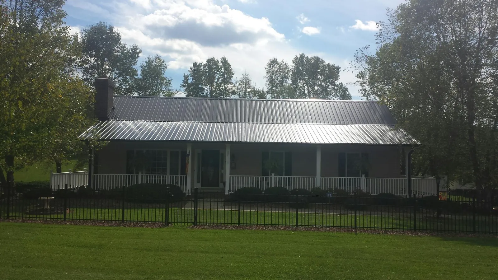 Gray metal roof on a brick ranch with a full width front porch — Gutter Guard Installation work by our crew in Saint Georges
