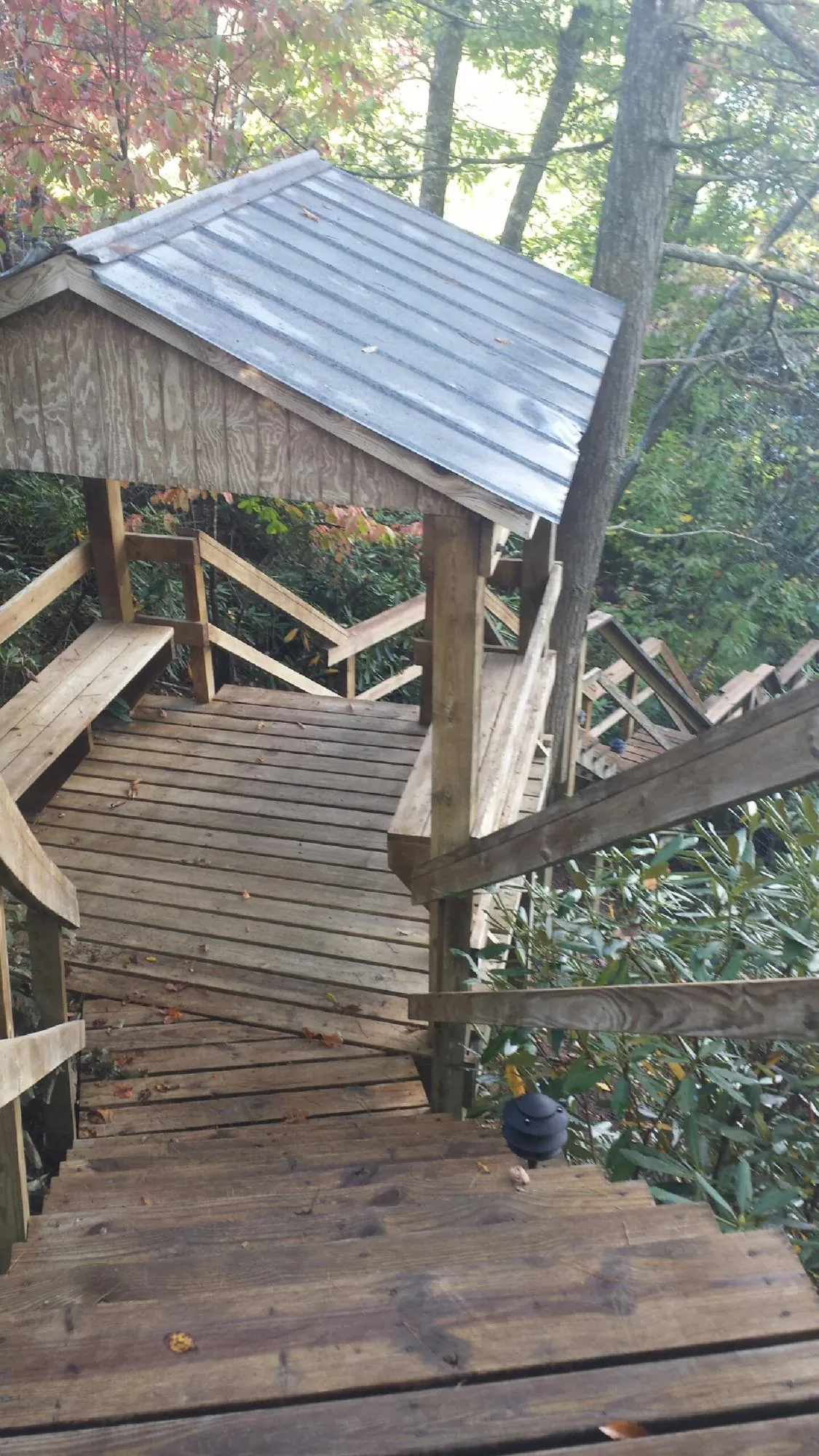 Metal roofed shelter over wooden steps on a wooded walkway — Skylight Repair & Installation work by our crew in Saint Georges