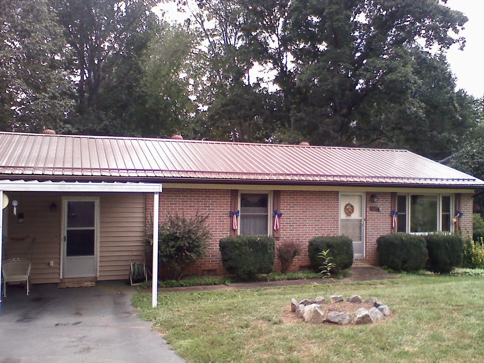 Bronze metal roof and carport on a brick ranch home — Roof Repair work by our crew in Saint Georges