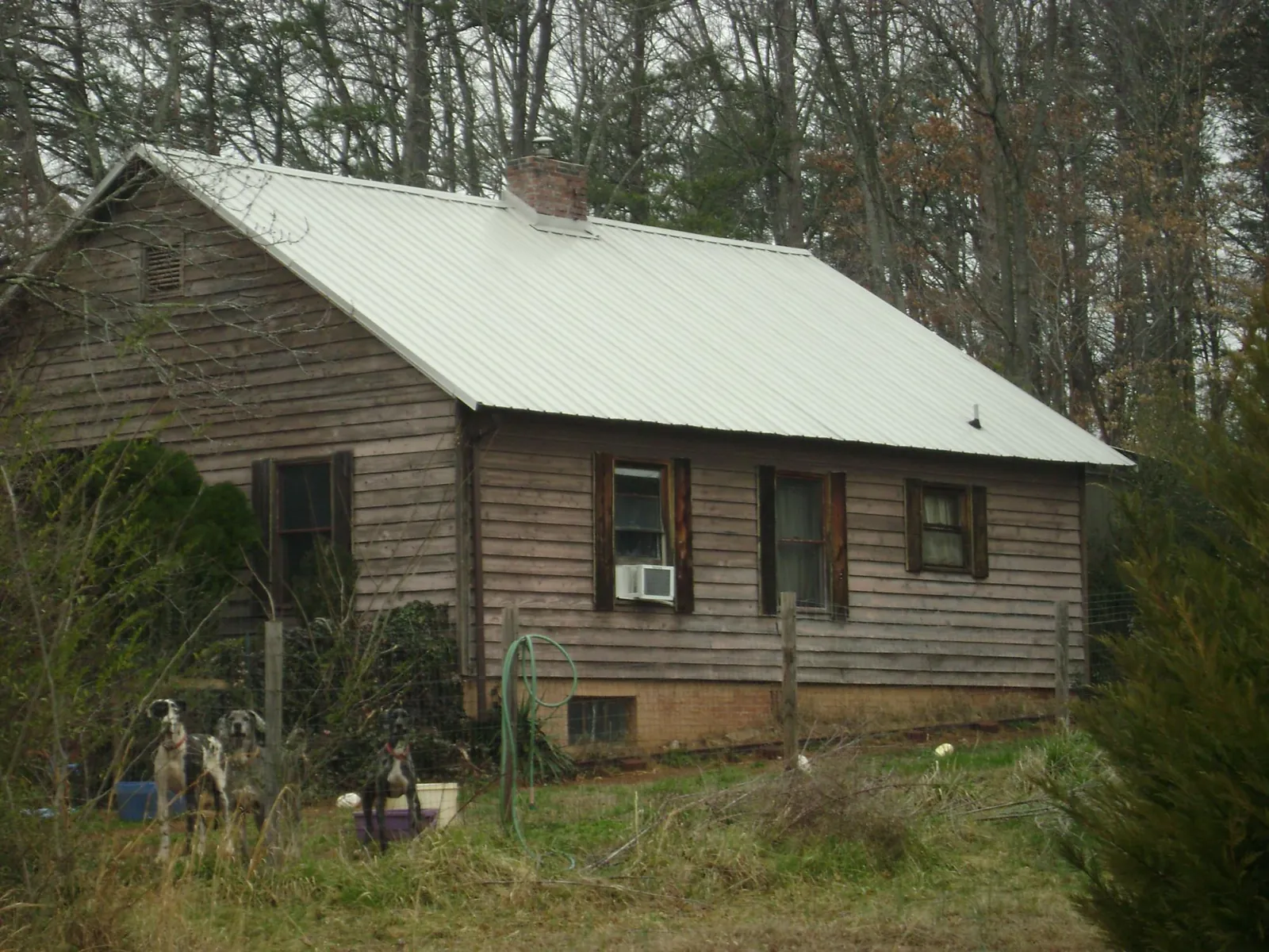 White metal roof on an old wood sided farmhouse, from a Metal Roof Installation job in Saint Georges